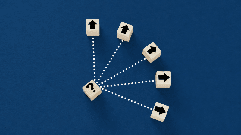 Wooden blocks with a question mark and branching arrows on a dark blue background.